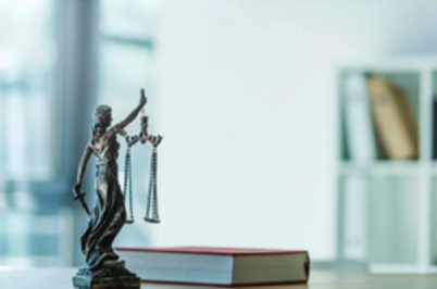 Imagem da notícia Imagem de estátua da Justiça e livro sobre a mesa
