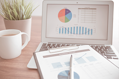 Imagem da notícia Imagem de notebook com tela de gráficos estatísticos, prancheta, caneca e vaso de planta sobre a mesa, todos em tons claros