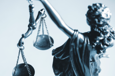 Imagem da notícia Imagem em formato horizontal. Representação de uma escultura metálica da figura da Justiça. Aparece apenas a parte superior do corpo e o braço direito erguido. A figura segura uma balança com duas correntes, cada uma sustentando um prato circular. Os dois pratos estão suspensos e aparentam estar no mesmo nível. A escultura tem acabamento em tom cinza metálico. O fundo é claro, em tom branco ou azul muito claro, sem outros elementos visíveis.