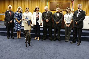 Foto da entrega do troféu do Prêmio Justiça do Trabalho Acessível, em que estão presentes e alinhados, em pé: Ministro Augusto César Leite de Carvalho, Juíza do Trabalho do TRT 2 Eliane Aparecida da Silva Pedroso, Desembargadora do Trabalho, Presidente da Comissão Permanente de Acessibilidade e Inclusão do TRT 2, Ana Maria Moraes Barbosa Macedo, que está segurando o troféu, servidora Thays Martinez e seu cão guia Sophie, Ministro Maurício Godinho Delgado, Ministro Cláudio Mascarenhas Brandão, servidora Adriana Domanoski Gurniak e Ministro Lélio Bentes Corrêa.