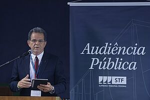 Imagem da Notícia Waldir Florindo ao lado de um banner escrito "Audiência Pública STF"