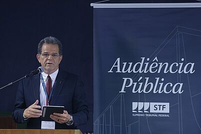 Imagem da notícia Waldir Florindo ao lado de um banner escrito "Audiência Pública STF"