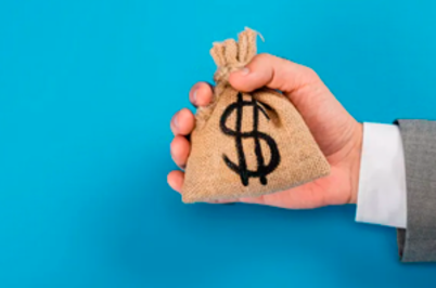 Imagem da notícia Mão segurando saquinho de dinheiro, com símbolo de cifrão, em fundo azul