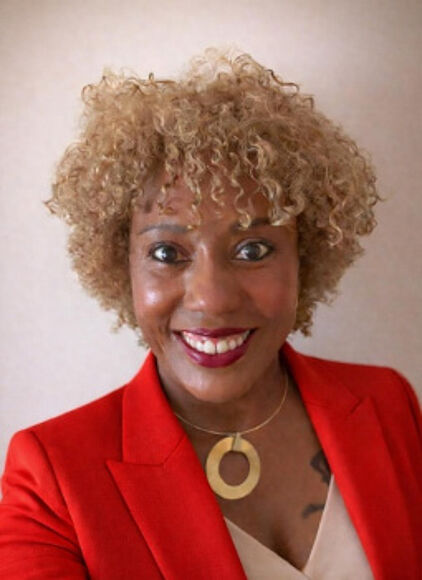Fernanda Izidio de Oliveira Cimino (Servidora do TRT-2 indicada para o Comitê de 1º Grau) Mulher negra, cisgênero, pertecente à geração Xennial, mãe do Robin. Na imagem aparece sorrindo, com cabelos crespos atualmente loiros, vestindo blusa bege, blazer vermelho e colar dourado.