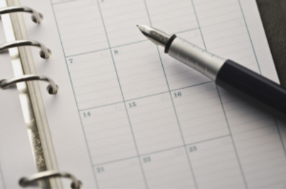 Imagem da notícia caneta repousa sobre uma agenda aberta, com encadernação em espiral e quadrados que representam as datas