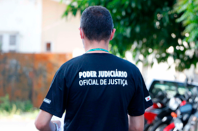 Imagem da notícia Imagem de homem visto de costas usando camiseta escura escrito "Poder Judiciário - Oficial de justiça"