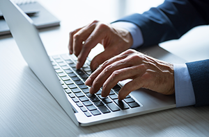 Imagem da Notícia Imagem de mãos de homem digitando em teclado do notebook