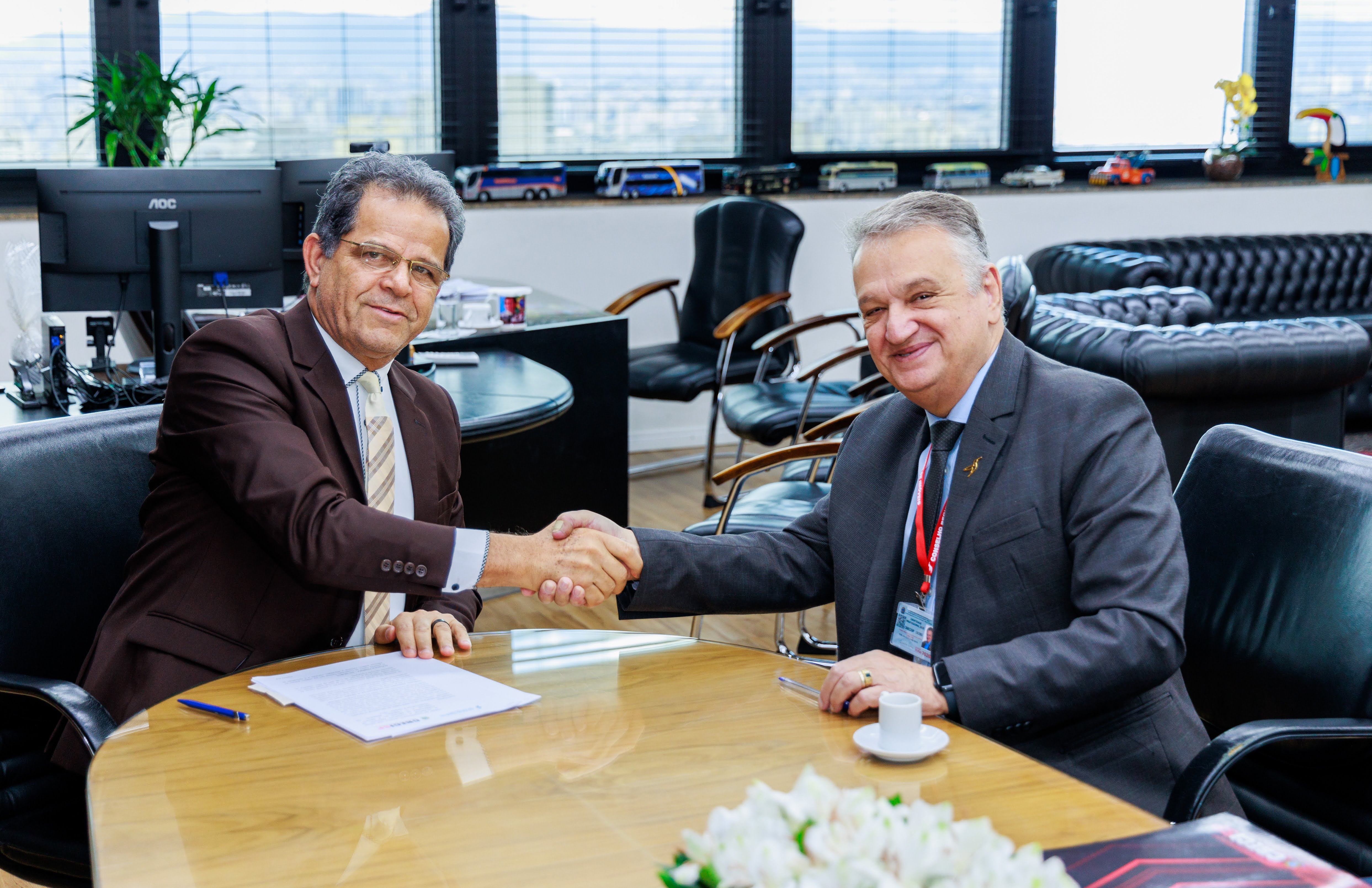 Presidente Valdir Florindo (à esquerda) com o presidente José Augusto Viana Neto (à direita) sentados à mesa e apertando as mãos