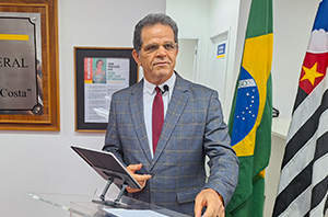 Imagem da Notícia Presidente do TRT-2 em púlpito com bandeiras do Brasil e de São Paulo atrás