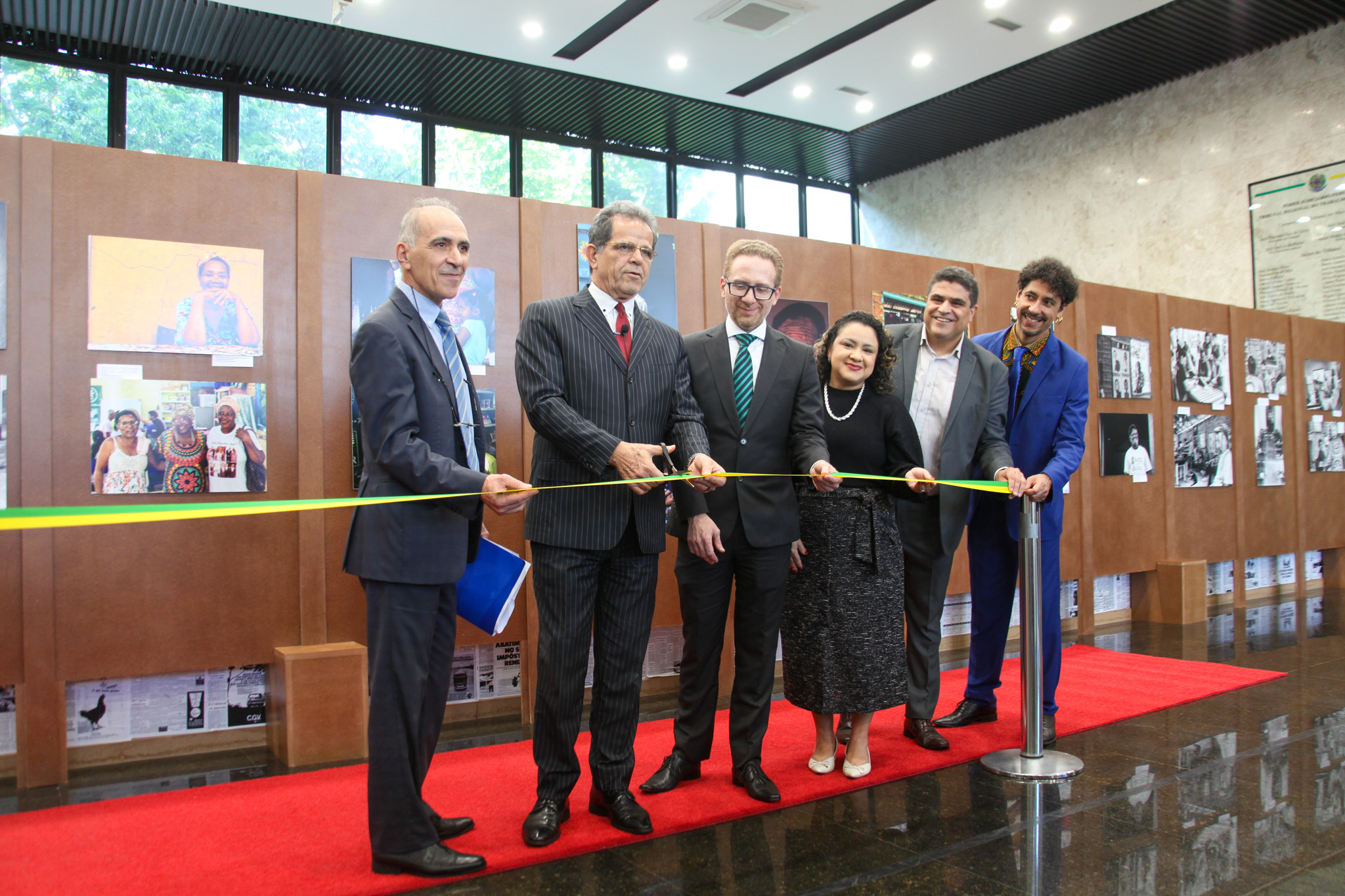 Waldir Florindo corta a fita de abertura da exposição ao lado dos demais presentes na cerimônica, citados no texto da notícia
