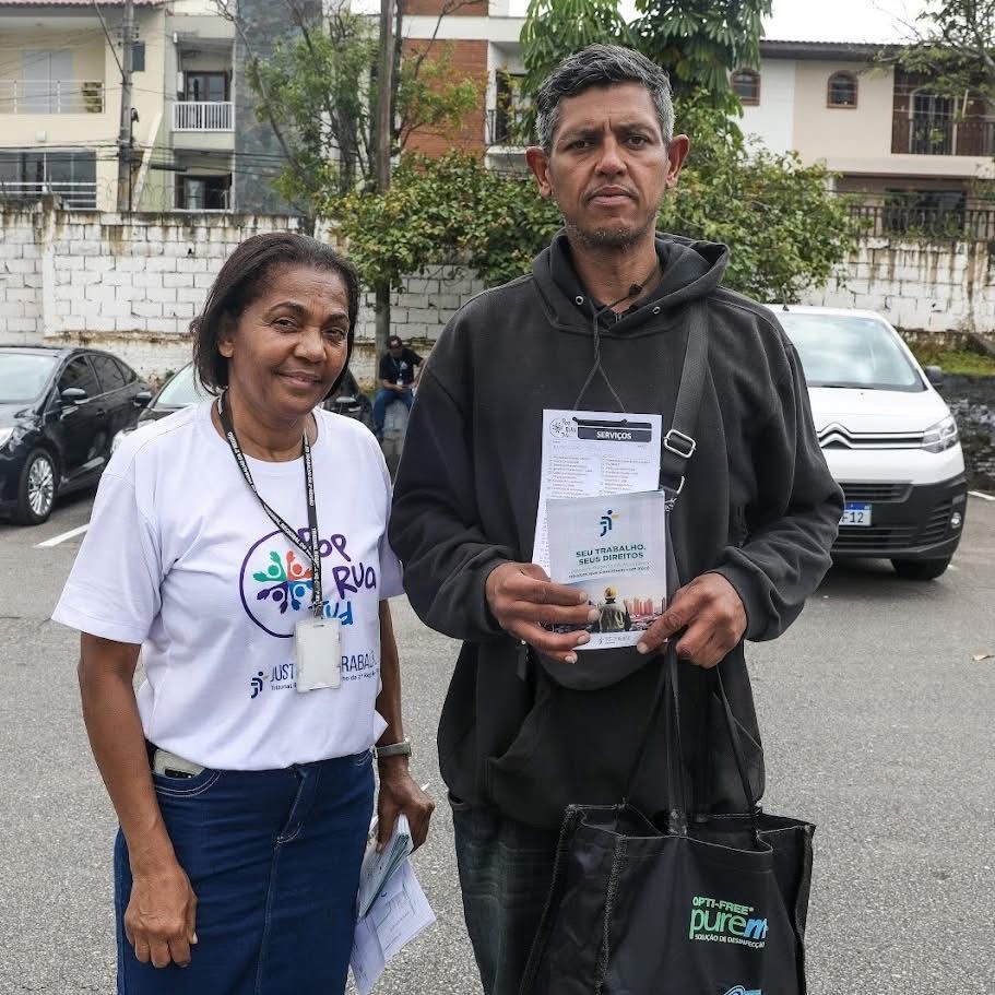 Diretora da UAO do TRT-2 Dulcinea Figueiredo posa com cidadão segurando o flyer da Cartilha de Linguagem Simples