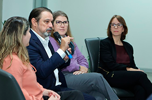 Imagem da Notícia Imagem do desembargador Antero Arantes Martins falando no microfone, com participantes sentadas ao lado, em roda