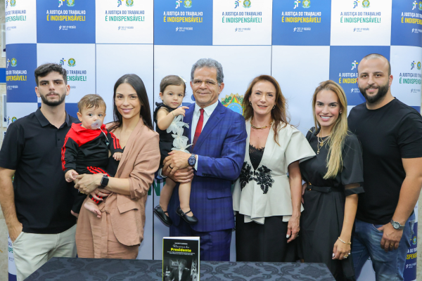 pres. Valdir Florindo posa com sua família em frente ao painel com os logos "A Justiça do Trabalho é Indispensável"