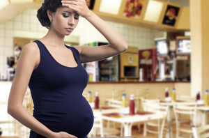 Imagem da Notícia Grávida em lanchonete, com uma mão na testa e outra na barriga