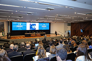 Imagem da Notícia Auditório do TRT com pessoas assistindo a uma palestra diante de uma grande tela de projeção